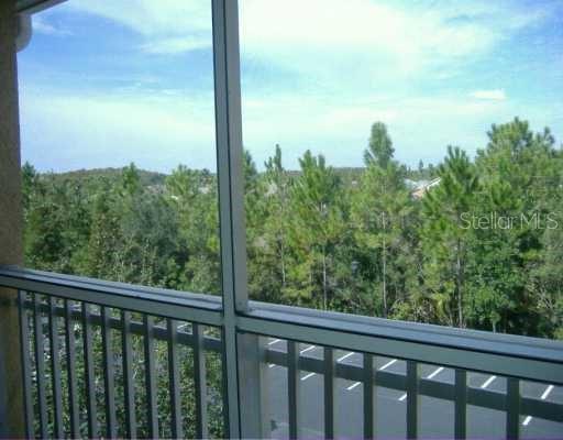 A view from a screened-in balcony overlooking a parking lot and a dense forest — 18001 RICHMOND PLACE DRIVE UNIT 1033, TAMPA, FL