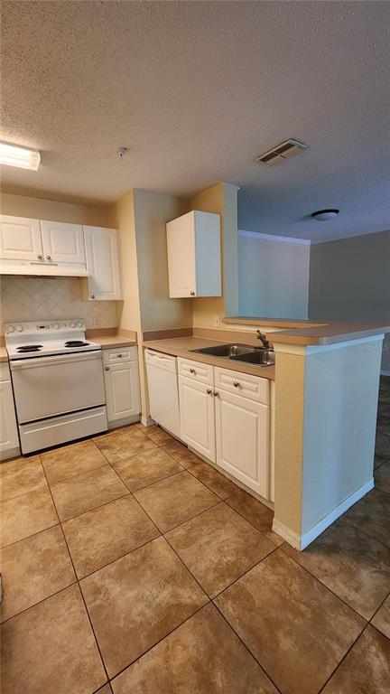 A kitchen features white cabinets, a white stove, and brown tile flooring — 18001 RICHMOND PLACE DRIVE UNIT 1033, TAMPA, FL