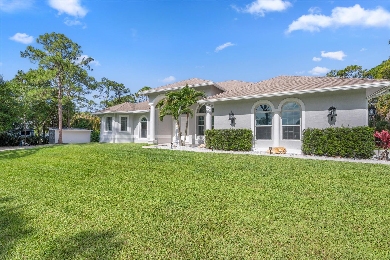 A single-story house with a light gray exterior, arched windows, and a large front lawn — 17038 N 61st Pl Place N, FL 33470, FL