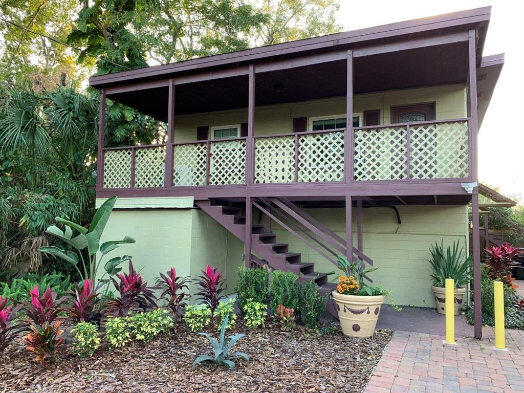An elevated house with a wooden porch, lattice railings, and stairs leading to the entrance — 2512 MUSSELWHITE AVENUE UNIT 3, ORLANDO, FL