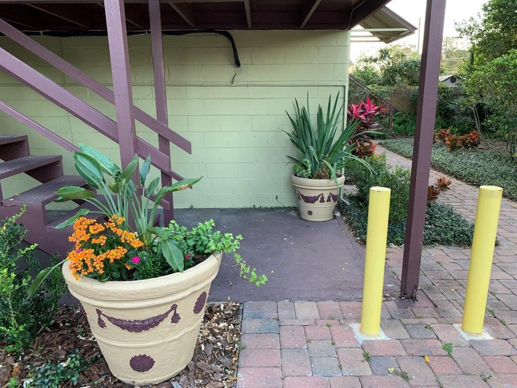 Two large decorative planters sit on a paved patio beneath a wooden staircase — 2512 MUSSELWHITE AVENUE UNIT 3, ORLANDO, FL