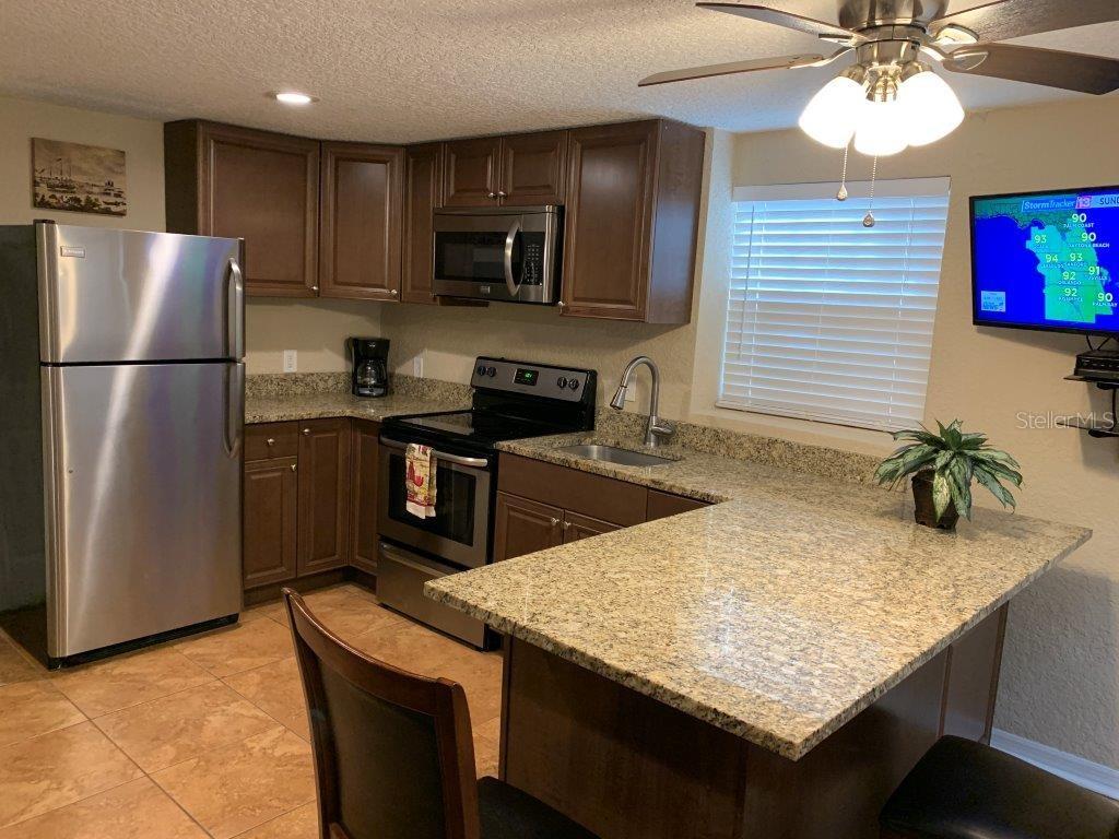 A kitchen features brown cabinets, granite countertops, stainless steel appliances, and a breakfast bar — 2512 MUSSELWHITE AVENUE UNIT 3, ORLANDO, FL