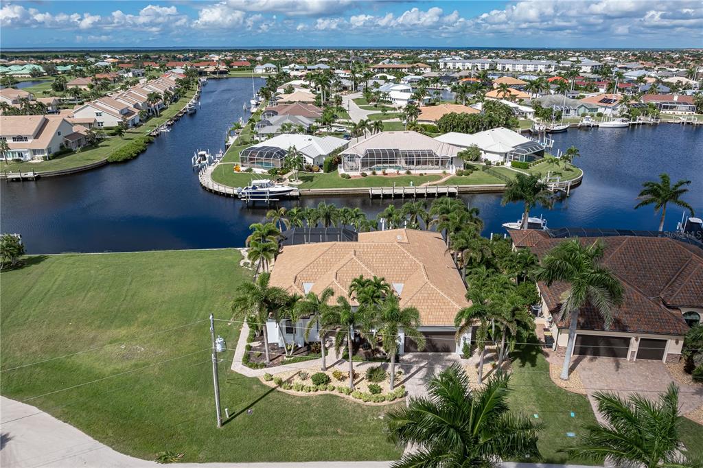 An aerial view shows a tan-roofed house with palm trees and a canal in Florida — 3615 TOWHEE COURT, PUNTA GORDA, FL