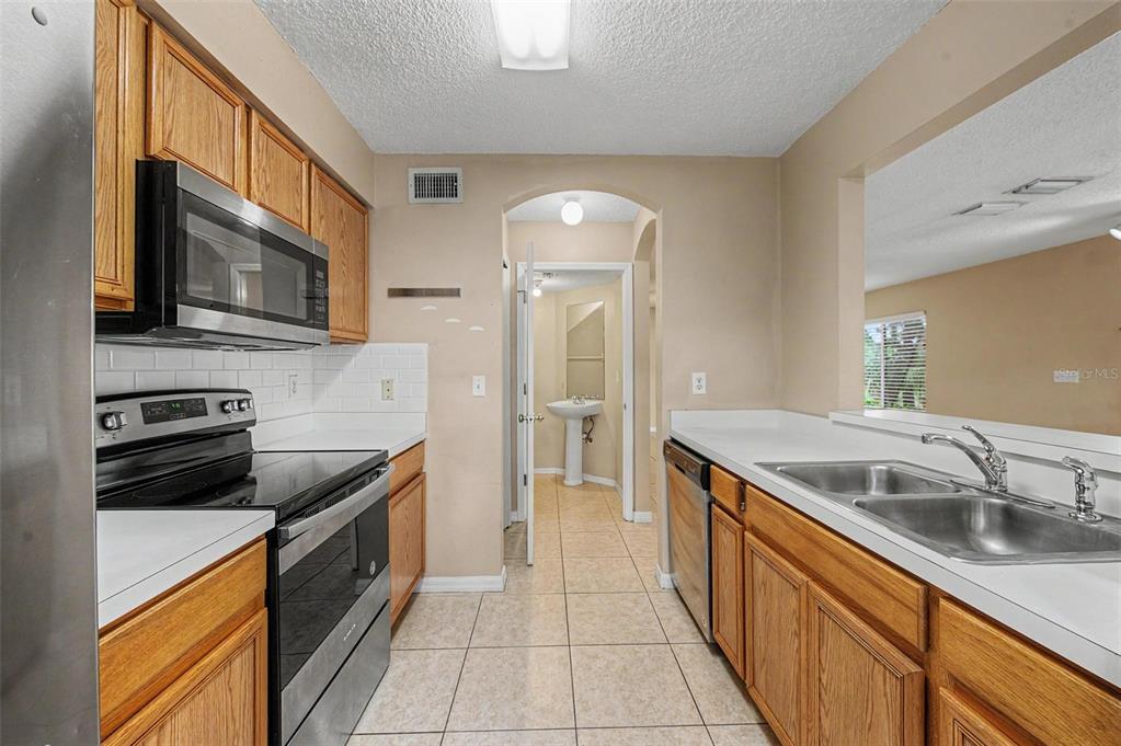 A kitchen with oak cabinets, stainless steel appliances, white countertops, and a tiled floor — 7434 E BANK DRIVE, TAMPA, FL