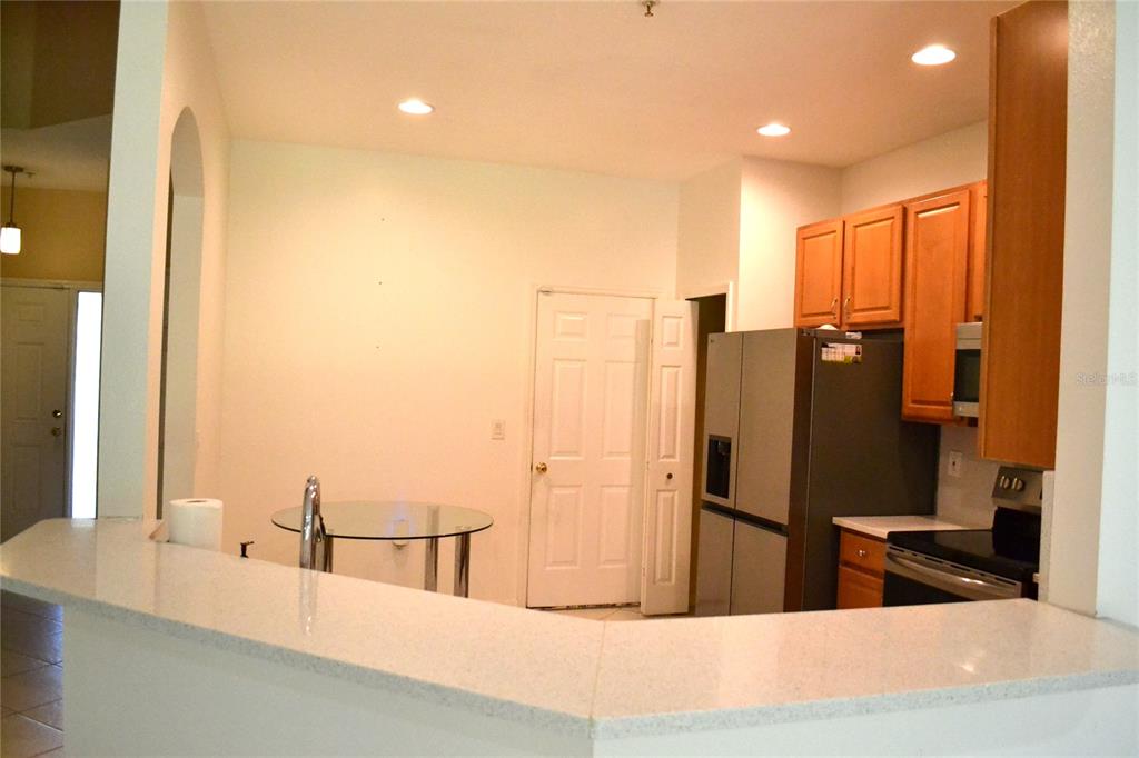 A kitchen features light countertops, wooden cabinets, stainless steel appliances, and a glass dining table — 11235 KAPOK GRAND CIRCLE, MADEIRA BEACH, FL