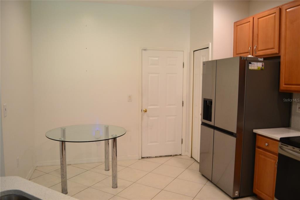 A kitchen dining area features a glass table, stainless steel refrigerator, and light-colored tile flooring — 11235 KAPOK GRAND CIRCLE, MADEIRA BEACH, FL