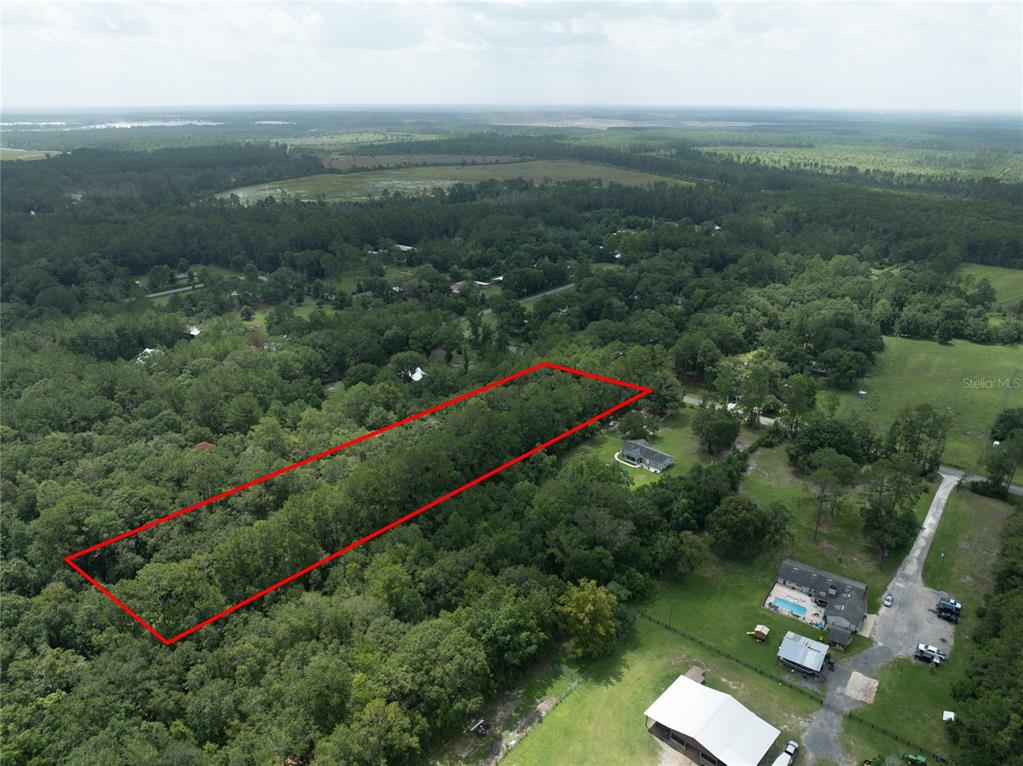 An aerial view shows a rectangular plot of land outlined in red amidst wooded surroundings — 0 SE 144TH STREET, STARKE, FL