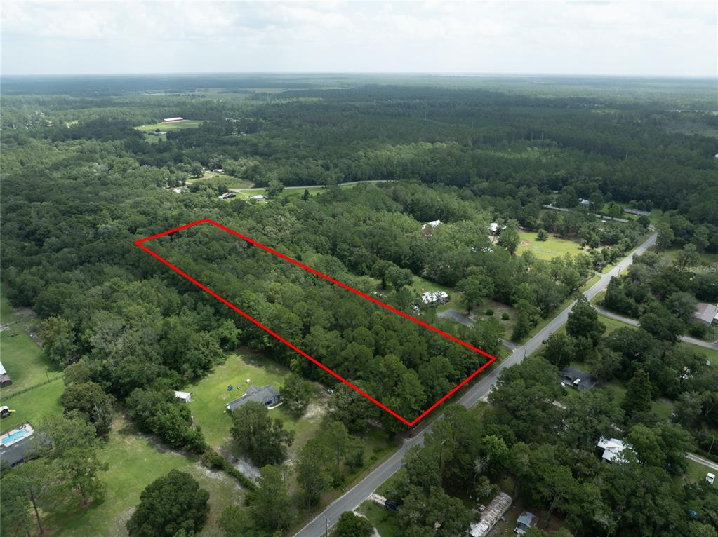 An aerial view shows a rectangular, tree-covered plot of land outlined in red — 0 SE 144TH STREET, STARKE, FL