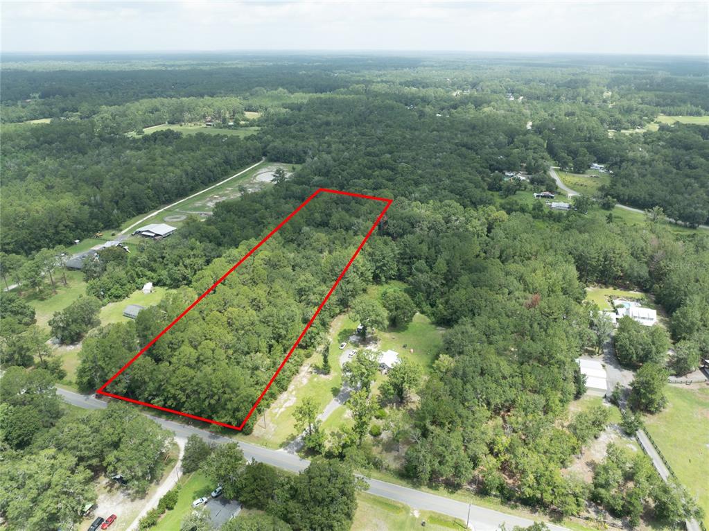 An aerial view shows a rectangular, tree-covered plot of land outlined in red — 0 SE 144TH STREET, STARKE, FL