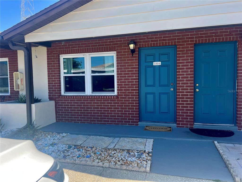 A brick exterior features two blue doors and a window under a white roofline — 24862 US HIGHWAY 19 N UNIT 1804, CLEARWATER, FL