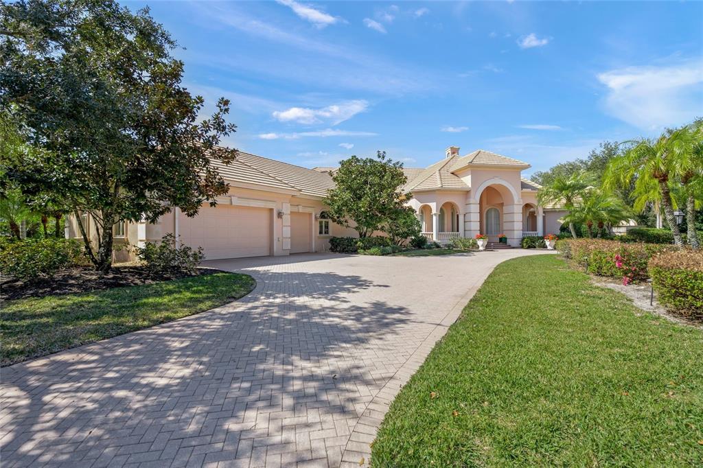 A single-story house with a paved driveway, a three-car garage, and arched entryway features — 6702 CHANCERY PLACE, UNIVERSITY PARK, FL