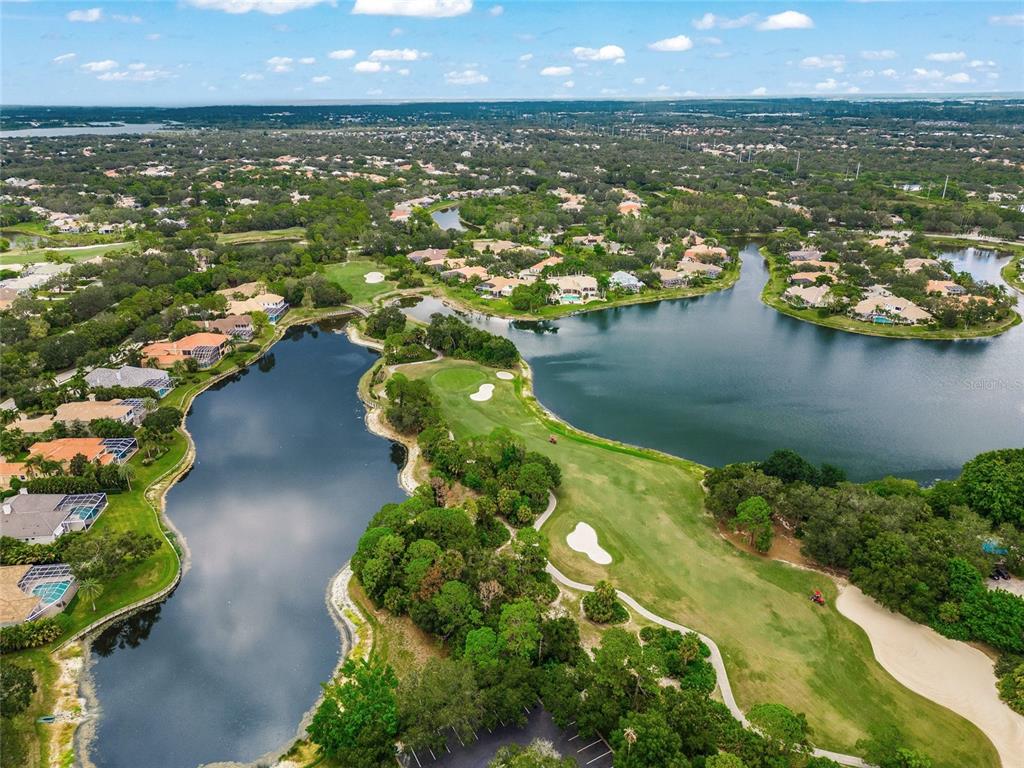 An aerial view shows a golf course fairway surrounded by a lake and residential homes — 6702 CHANCERY PLACE, UNIVERSITY PARK, FL