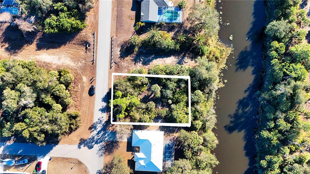 An aerial view shows a rectangular vacant lot bordered by a road, trees, and water — 0 ADELAIDE AVENUE, NORTH PORT, FL