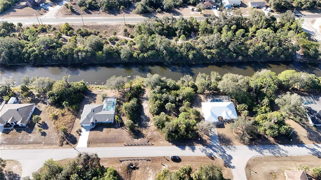 An aerial view shows houses with pools along a canal and a road — 0 ADELAIDE AVENUE, NORTH PORT, FL