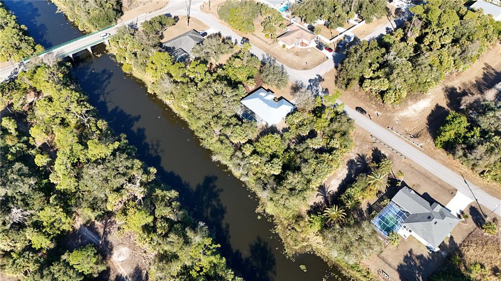 An aerial view shows a canal flowing past several houses with pools and wooded lots — 0 ADELAIDE AVENUE, NORTH PORT, FL