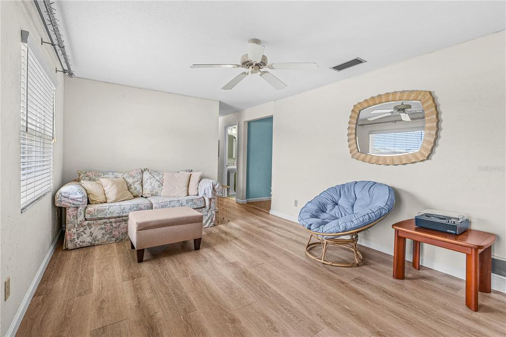 A living room features light wood flooring, a floral sofa, a blue chair, and mirror — 2955 CARRIAGE DRIVE, SOUTH DAYTONA, FL