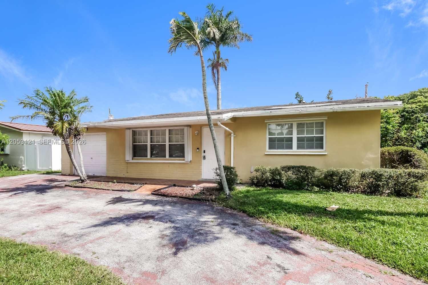 A single-story yellow house features a white front door, a garage, and two palm trees — COOPER CITY, FL