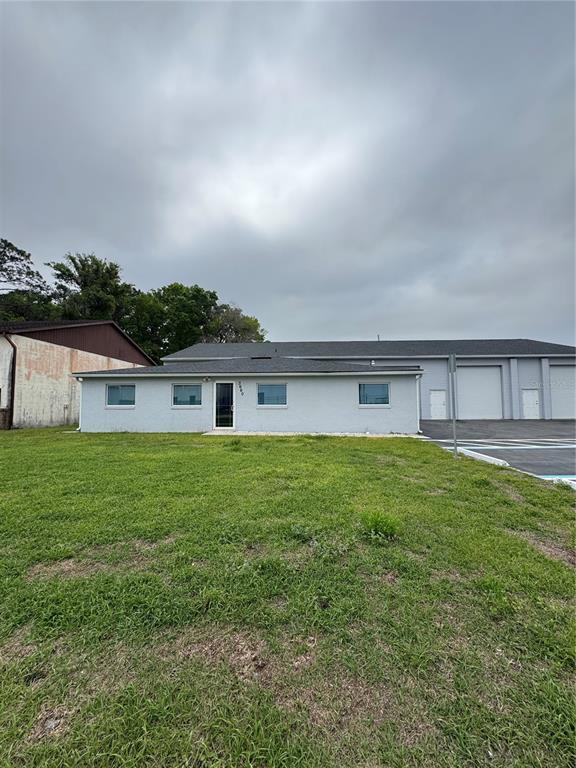 A single-story light gray building with a flat roof sits next to a warehouse — 3660 NE 42ND LANE, OCALA, FL