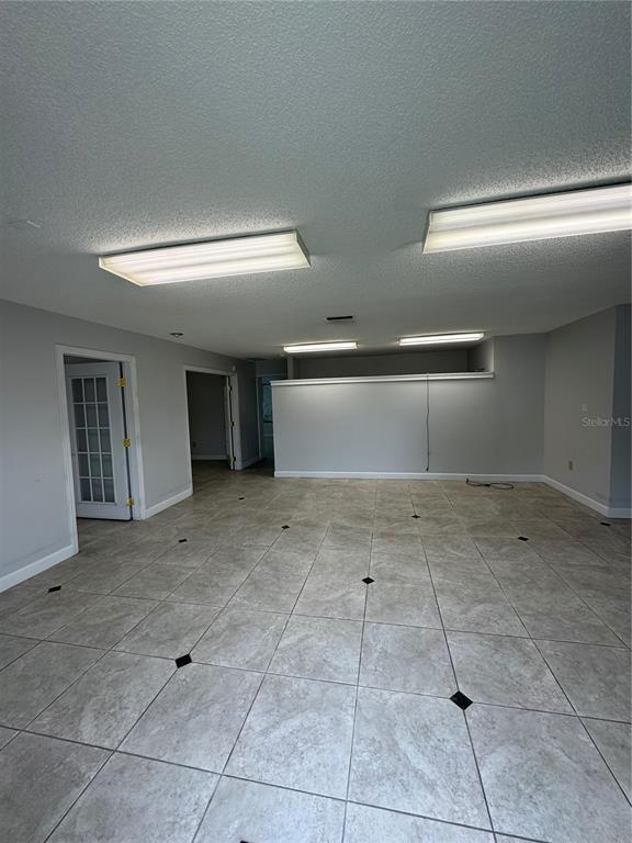 A room with gray walls, tiled flooring, and multiple rectangular ceiling light fixtures — 3660 NE 42ND LANE, OCALA, FL