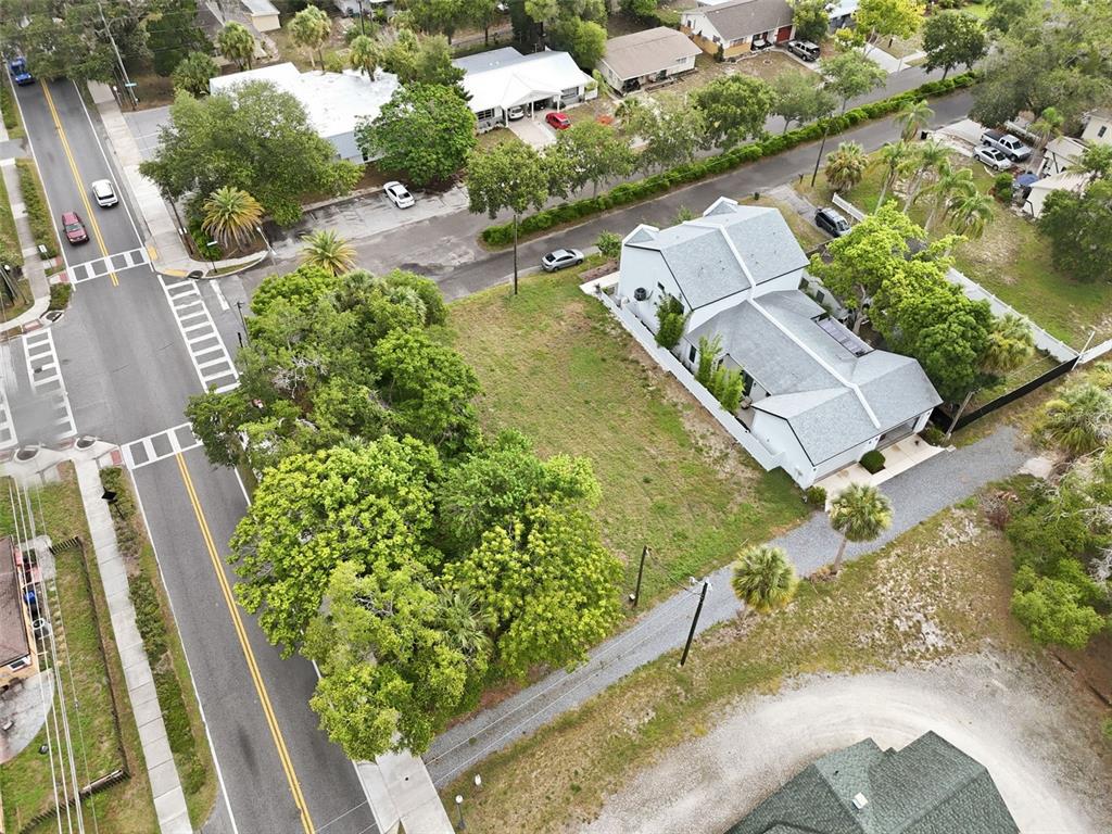 An aerial view shows a vacant lot with trees next to a white house — 5964 CENTRAL AVENUE, NEW PORT RICHEY, FL