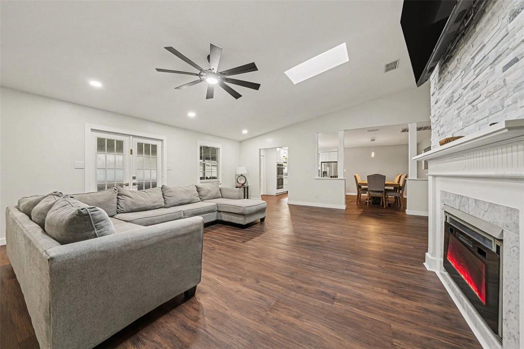 A living room with a gray sectional sofa, fireplace, and wood-look flooring — 1592 SKYLINE DRIVE, KISSIMMEE, FL