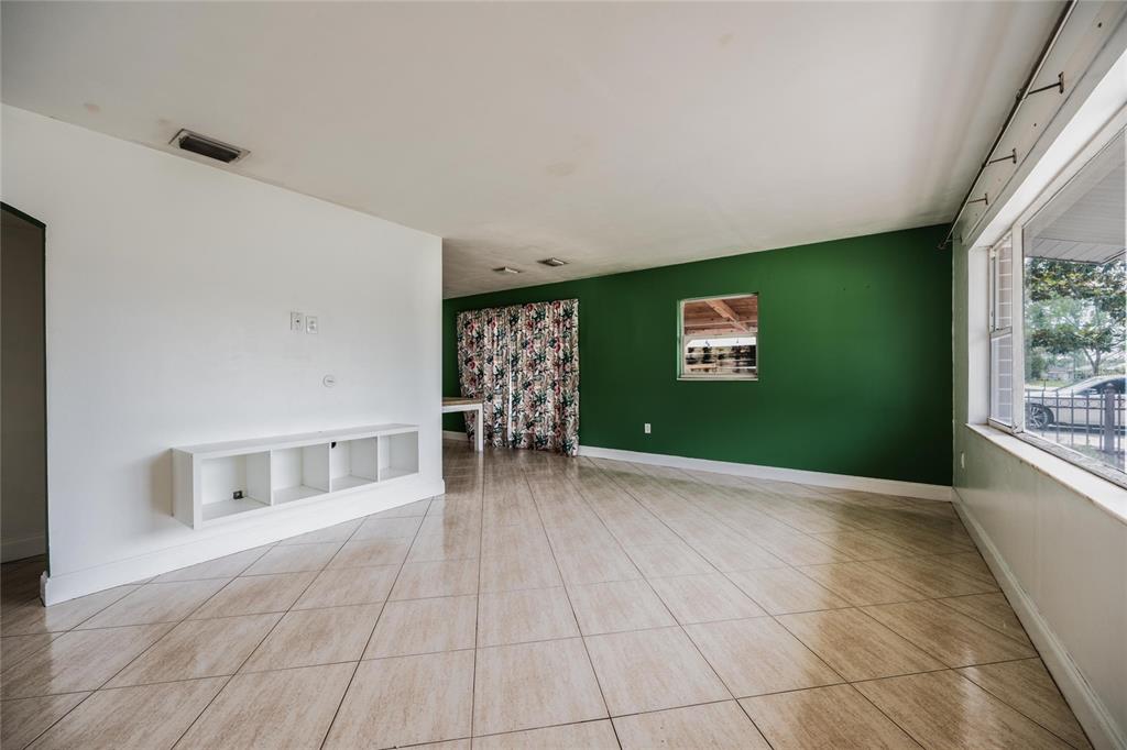 A living room features white walls, a green accent wall, tile flooring, and a window — 251 PINE TREE DRIVE, CASSELBERRY, FL