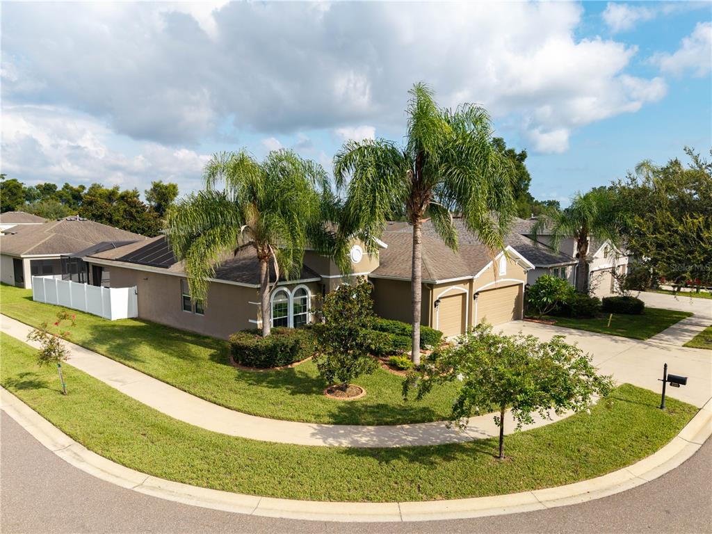 An exterior view of a single-story suburban house with a two-car garage and palm trees — 220 PARSONS WOODS DRIVE, SEFFNER, FL