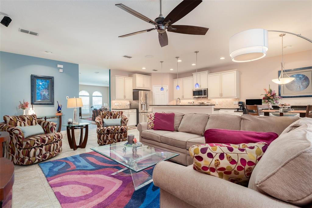 A living room with a patterned rug, beige sofa, two patterned armchairs, and an open kitchen — 220 PARSONS WOODS DRIVE, SEFFNER, FL