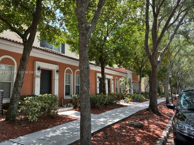 A row of orange townhouses with white trim and trees along a paved walkway — 2551 SW 99th Way, Miramar FL 33025, MIRAMAR, FL