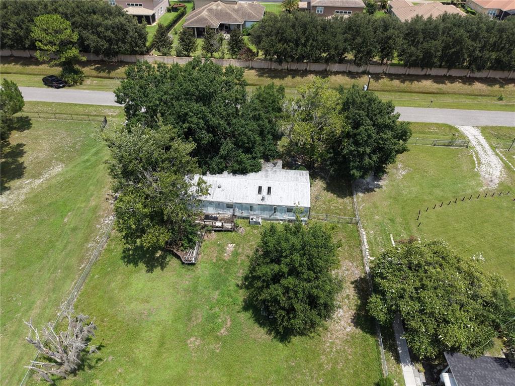 An aerial view shows a single-story house surrounded by large trees on a grassy lot — 18440 AMITYVILLE DR, ORLANDO, FL