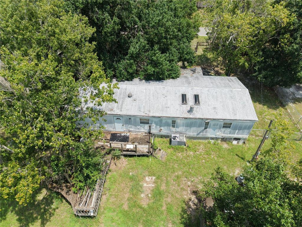 An aerial view shows a single-story house with a metal roof and a wooden deck — 18440 AMITYVILLE DR, ORLANDO, FL