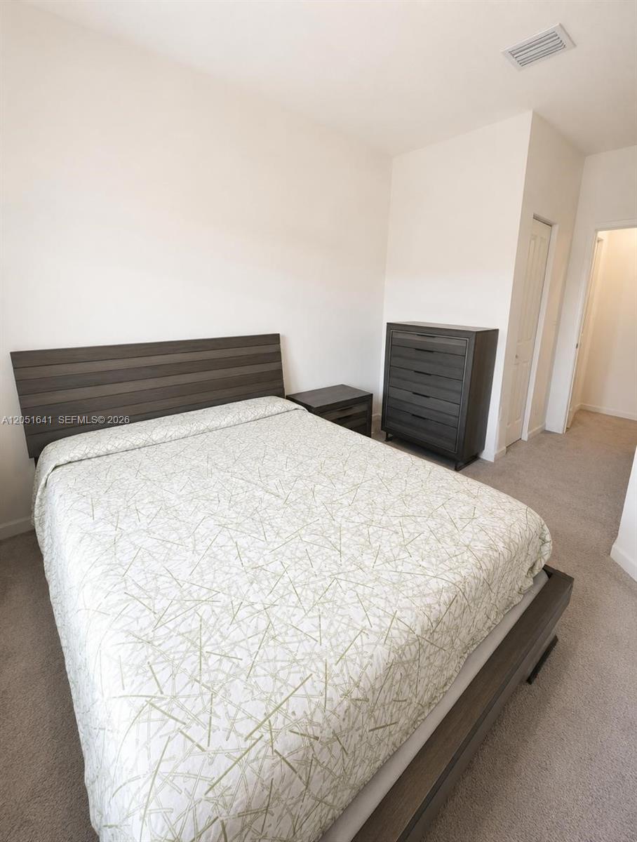 A bedroom features a dark wood bed frame, matching dresser, and a patterned white comforter — 25328 SW 108th Ct, Homestead FL 33032, HOMESTEAD, FL