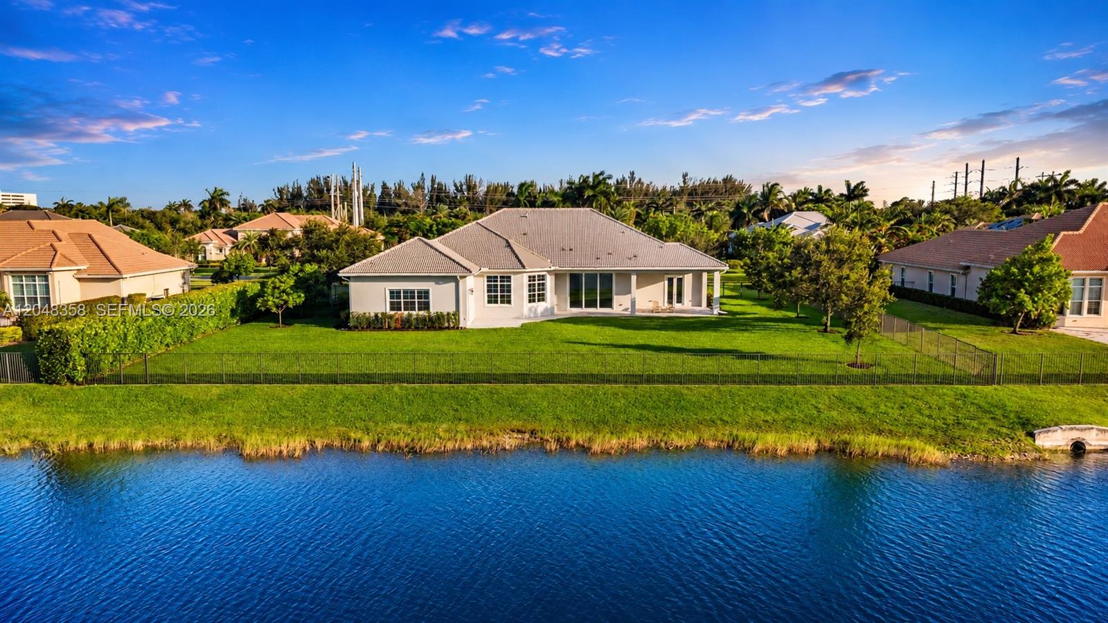 A rear view of a single-story house with a lawn and a lake — 5301 S Sterling Ranch Cir, Davie FL 33314, DAVIE, FL