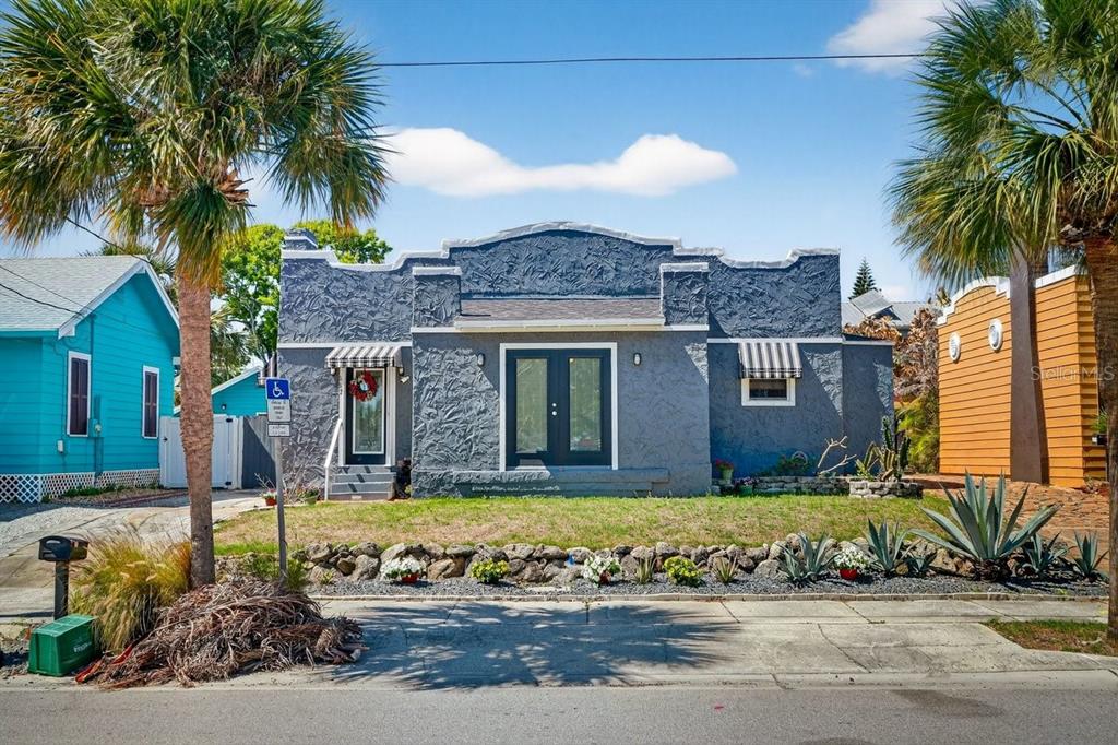 A single-story gray stucco house with a flat roof and double front doors — 112 S OLEANDER AVENUE, DAYTONA BEACH, FL
