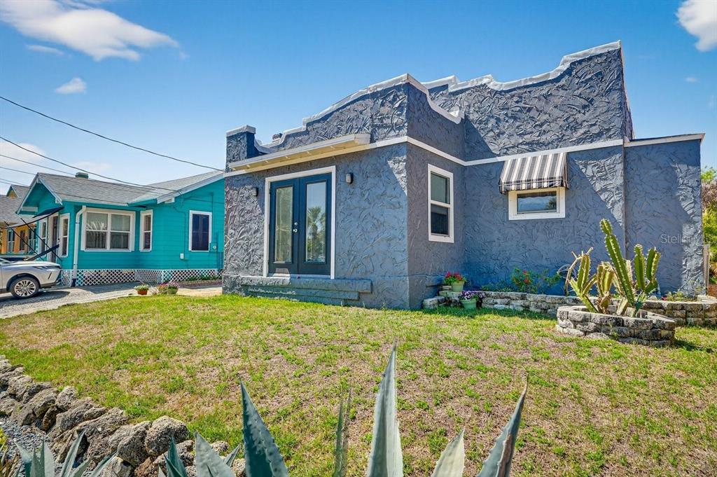 A blue stucco house with a textured facade and French doors sits on a lawn — 112 S OLEANDER AVENUE, DAYTONA BEACH, FL