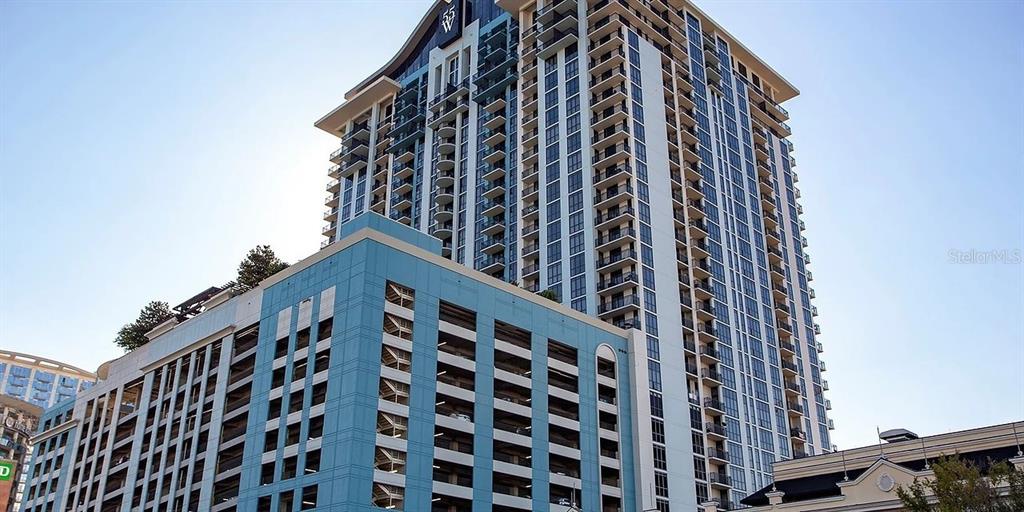 A tall residential high-rise building features a blue parking garage base and multiple balconies — 55-2 W CHURCH STREET, ORLANDO, FL