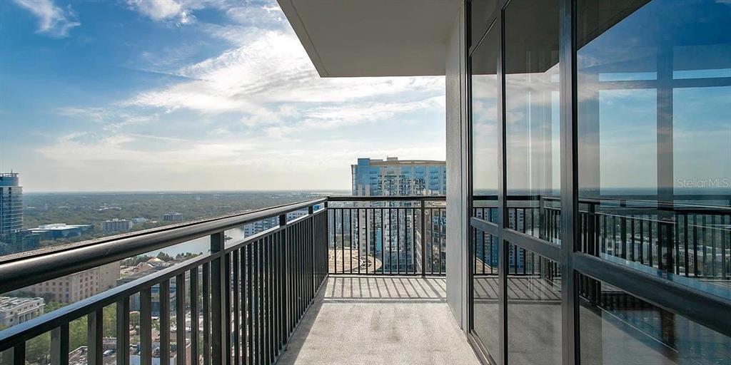 A high-rise balcony with a metal railing overlooks a city skyline under a blue sky — 55-2 W CHURCH STREET, ORLANDO, FL