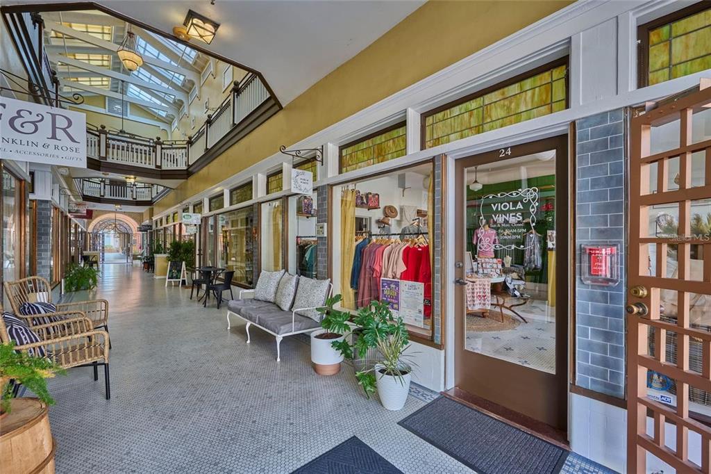 A covered outdoor shopping arcade features storefronts with glass doors, tiled floors, and seating areas — 230 E PARK AVENUE, LAKE WALES, FL