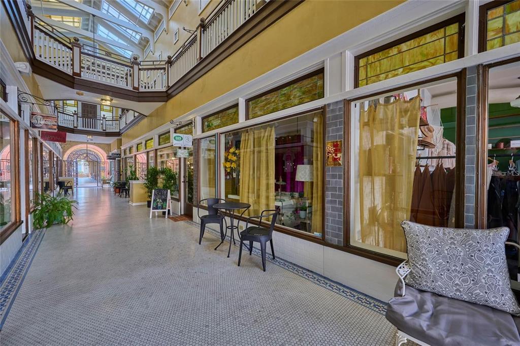 An indoor shopping arcade features a tiled walkway, storefronts with glass windows, and balcony railings — 230 E PARK AVENUE, LAKE WALES, FL