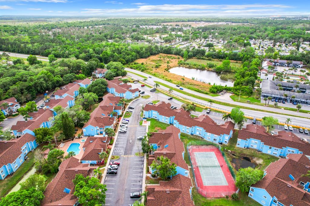An aerial view shows a multi-building apartment complex with a pool, tennis court, and parking — 2731 N POINCIANA BOULEVARD UNIT 114, KISSIMMEE, FL