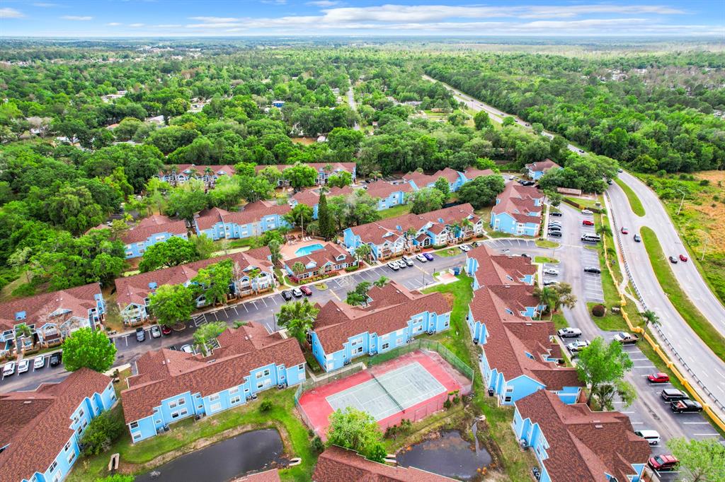 An aerial view shows a multi-building apartment complex with a swimming pool and tennis court — 2731 N POINCIANA BOULEVARD UNIT 114, KISSIMMEE, FL