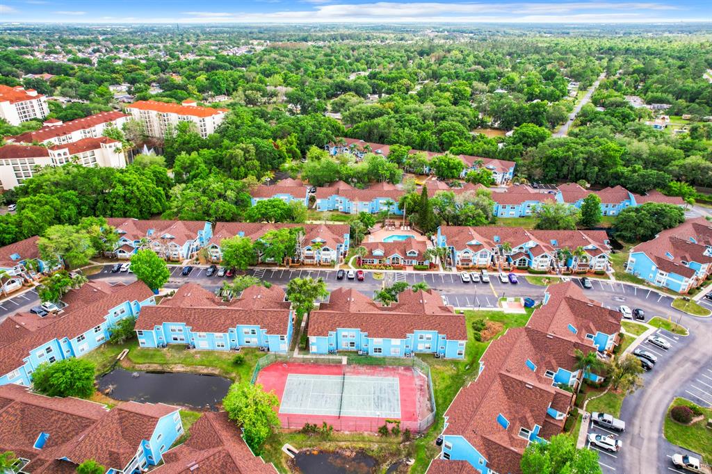 An aerial view shows a residential apartment complex with blue buildings, brown roofs, and tennis courts — 2731 N POINCIANA BOULEVARD UNIT 114, KISSIMMEE, FL