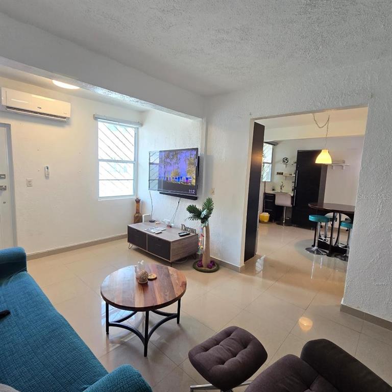 A living room with tile floors, a wall-mounted television, and an adjacent dining area — Doncella PLAZA COND UNIT 2, SAN JUAN, PR