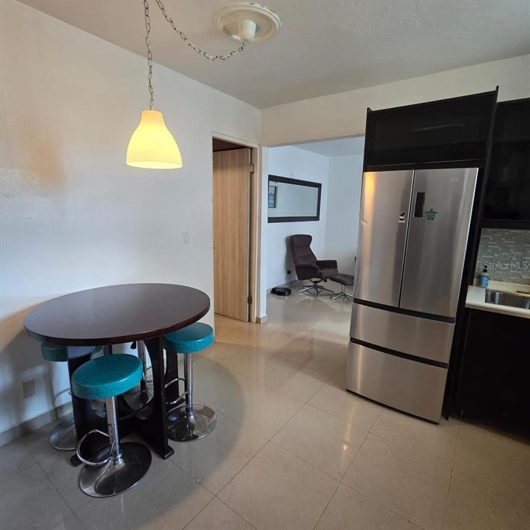 A dining area with a round table and stools sits next to a stainless steel refrigerator — Doncella PLAZA COND UNIT 2, SAN JUAN, PR
