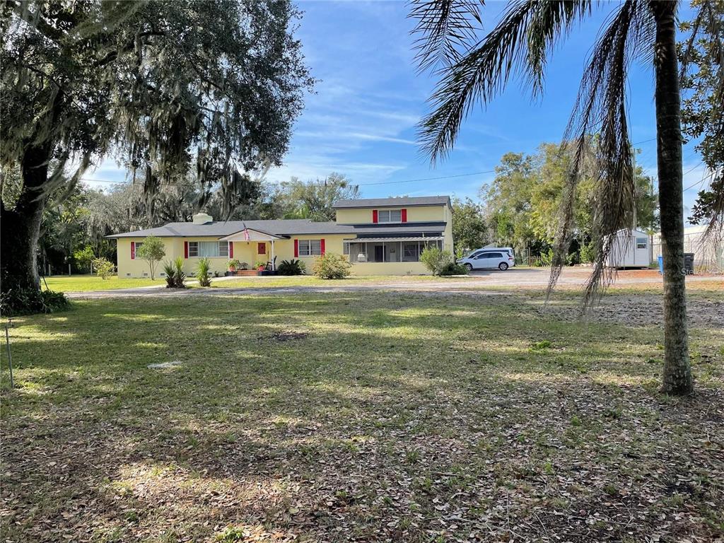 A yellow two-story house with red shutters sits on a large, grassy lot — 750 CHARLIE TAYLOR ROAD, PLANT CITY, FL