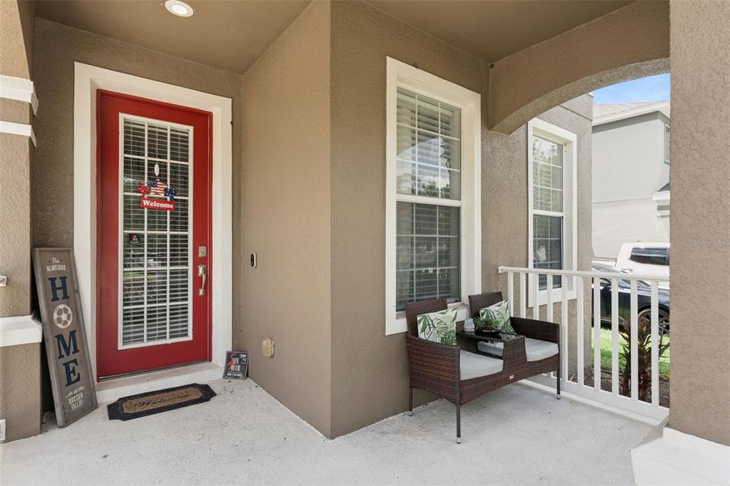 A covered front porch features a red door, a seating set, and a decorative sign — 9528 PICCADILLY SKY WAY, ORLANDO, FL