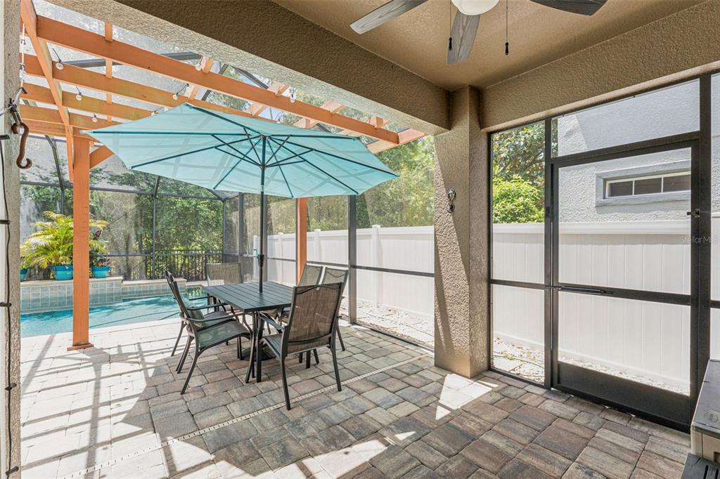 A covered patio with a dining set, pool, and screen enclosure — 9528 PICCADILLY SKY WAY, ORLANDO, FL