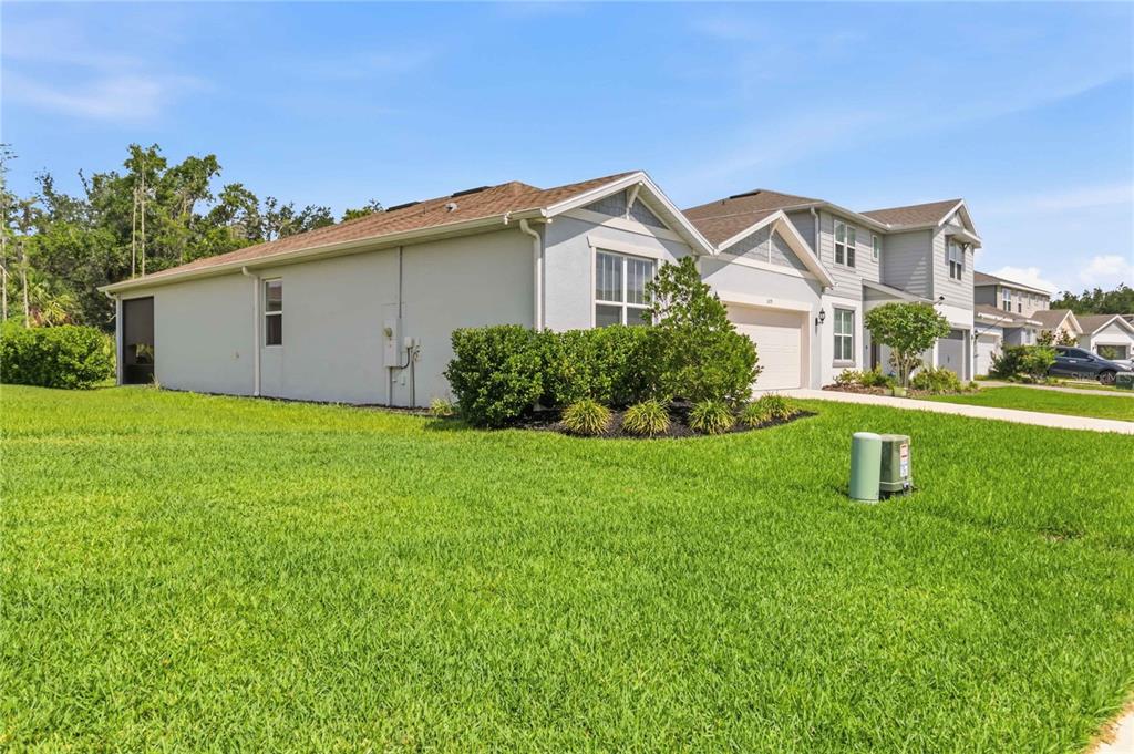 A side view of a light-colored suburban house with a large green lawn — 5179 ROYAL POINT AVENUE, KISSIMMEE, FL