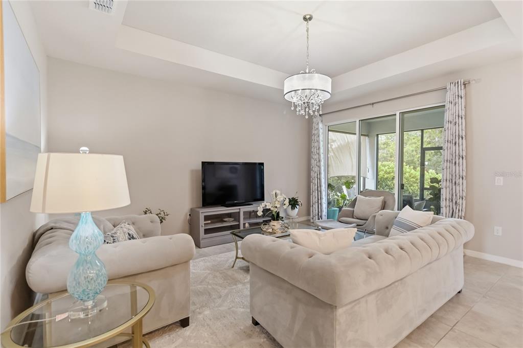 A living room features two tufted sofas, a television on a console, and a crystal chandelier — 5179 ROYAL POINT AVENUE, KISSIMMEE, FL