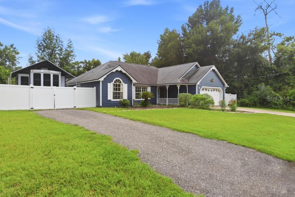 A blue single-story house with a gravel driveway and a white vinyl fence — 1714 20TH STREET, ORANGE CITY, FL